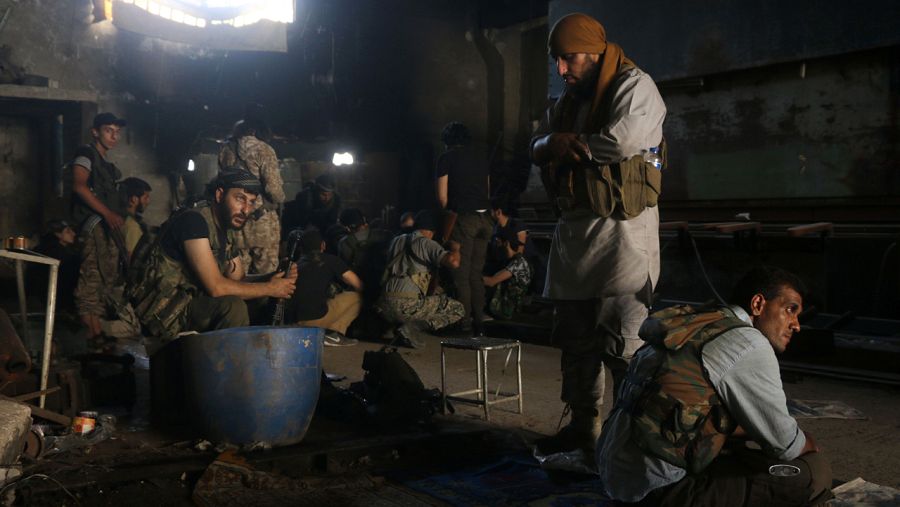 Milicianos rebeldes hacen una parada para el rezo en el barrio de Ramusa en Alepo