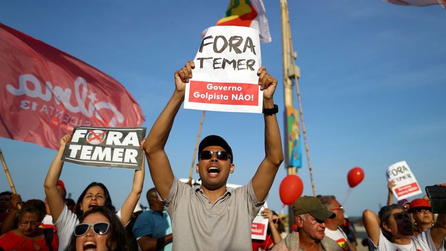 Manifestantes en Río de Janeiro, horas antes de la ceremonia de inauguración de los Juegos Olímpìcos el pasado viernes 5 de agosto, muestran carteles contra el presidente interino, Michel Temer.