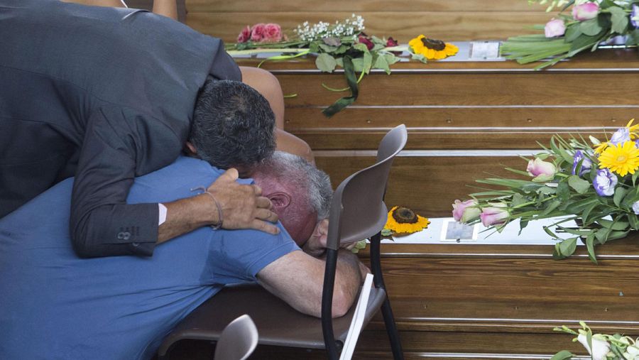Dos hombres lloran sobre el féretro de una de las víctimas del terremoto en el funeral en Ascoli Piceno