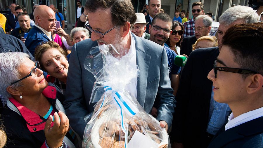Una simpatizante regala una bolsa de rosquillas a Mariano Rajoy durante un paseo electoral en Pontedeume (A Coruña)