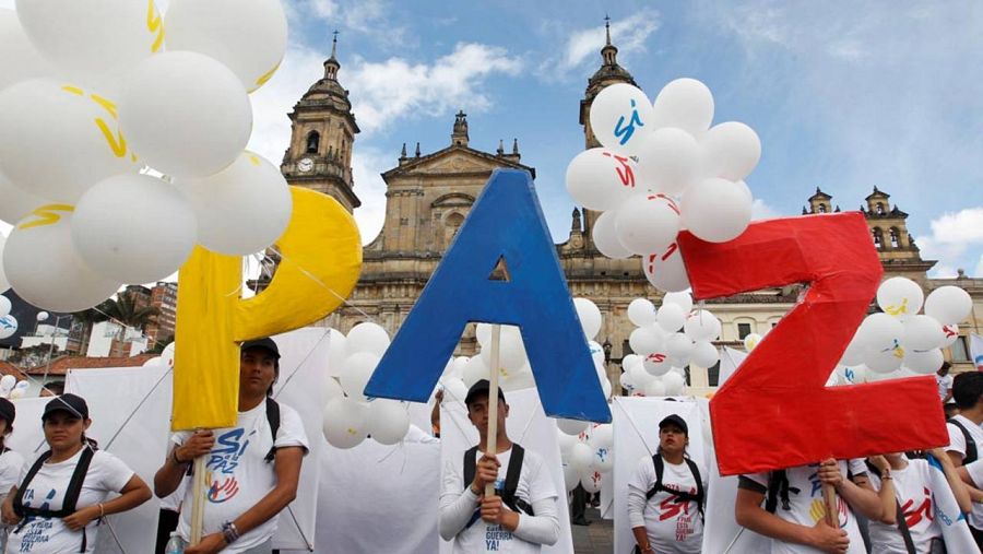 Varios asistentes a la ceremonia sostienen las letras que conforman la palabra PAZ