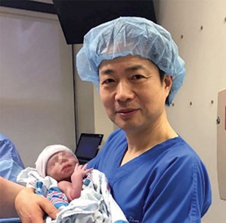 El científico especialista en fertilidad John Zhang, junto al bebé.