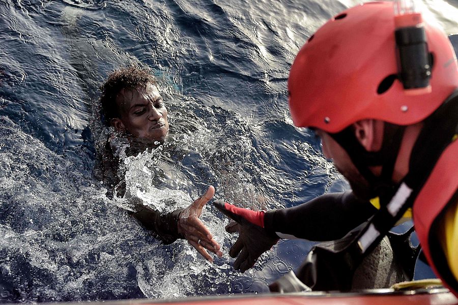 Un miembro de la ONG Proactiva Open Arms ayuda a sacar del agua a un migrante