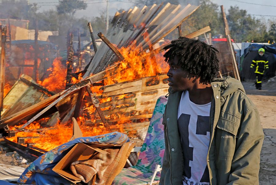 Un inmigrante pasa junto a la chabola que ha ardido en el 'jungla de Calais'