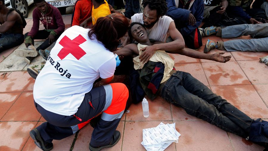 Un trabajador de la Cruz Roja asiste a uno de los inmigrantes que han saltado la valla fronteriza en Ceuta