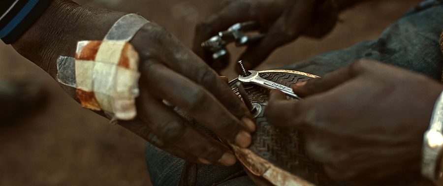 Un grupo de subsaharianos ajusta sus zapatillas para que le ayuden a trepar por la valla que impide el acceso a Melilla