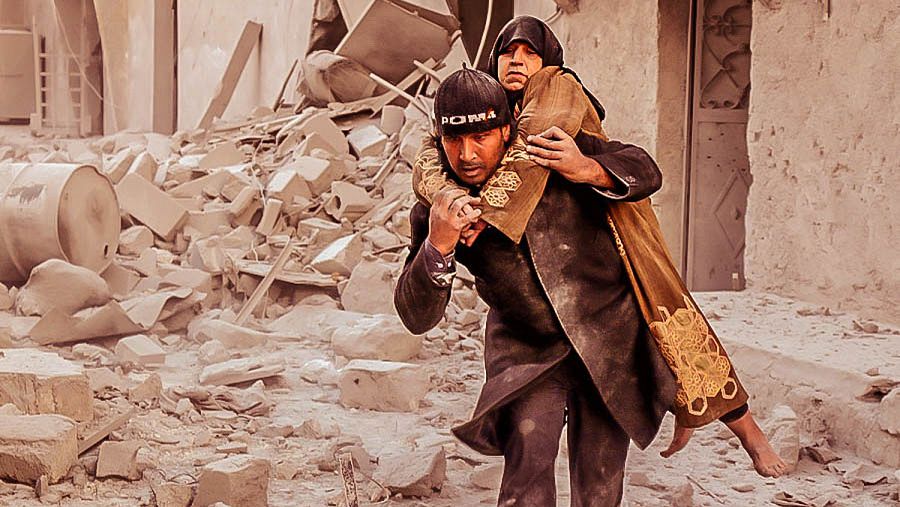 Un hombre ayuda a salir de entre los escombros de un edificio derribado a una mujer en Alepo, Siria.