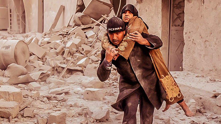 Un hombre ayuda a salir de entre los escombros de un edificio derribado a una mujer en Alepo, Siria.