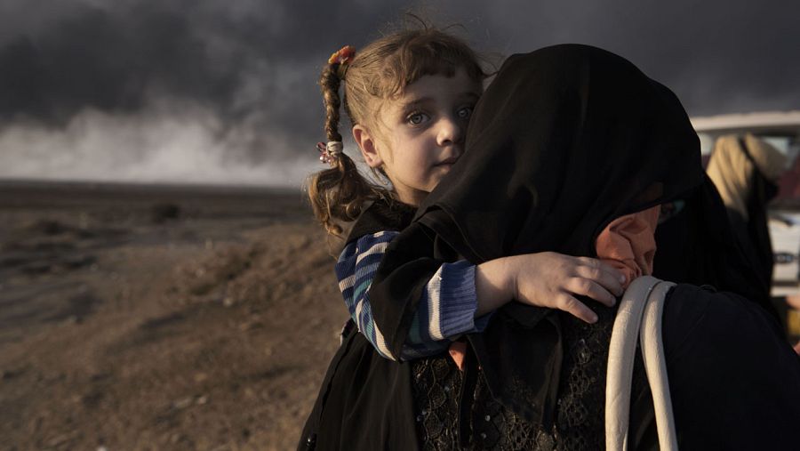 Una mujer desplazada lleva a su hija en el 'check point' de Qayyara, al sur de Mosul el 31 de octubre de 2016.