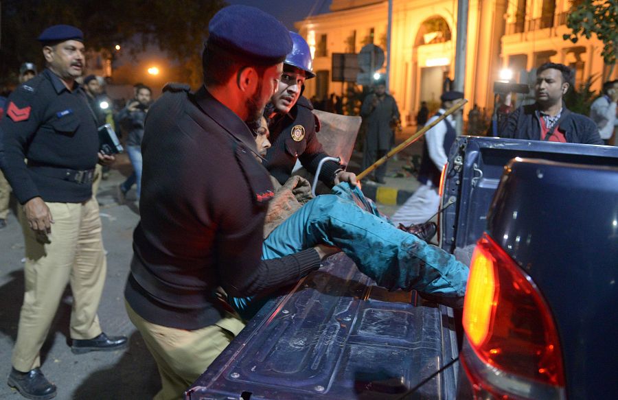 Un policía intenta trasladar a un herido en el atentado de Lahore