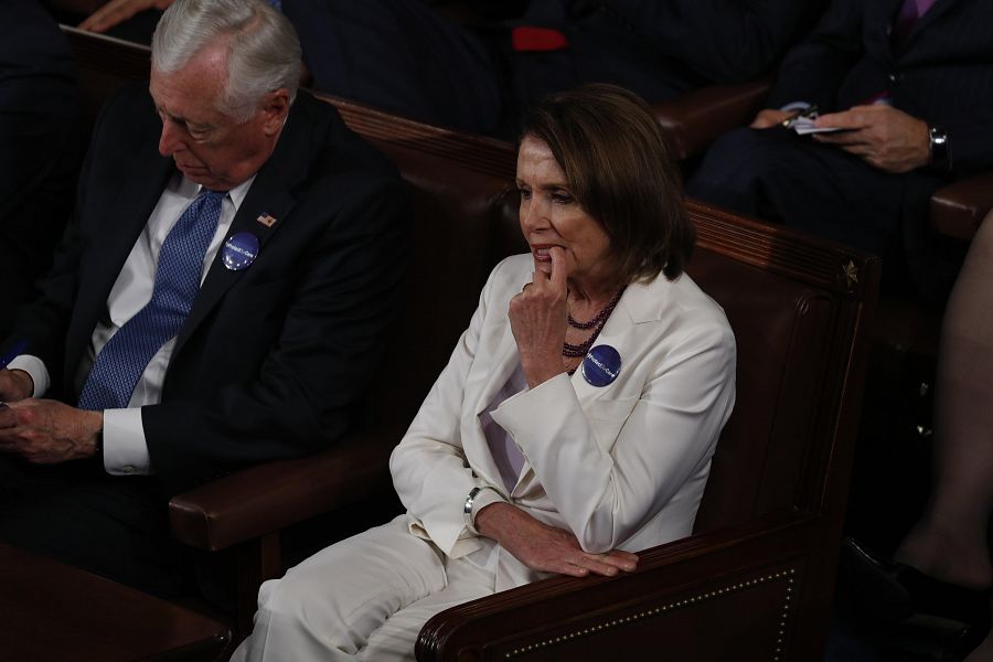 La líder de la minoría demócrata Nancy Pelosi, de blanco igual que el resto de congresistas demócratas, escucha el discurso de Trump.