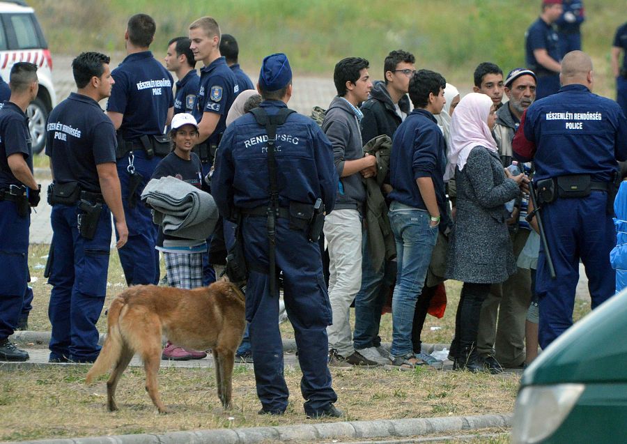 Solicitantes de asilo esperan, custodiados por la policía húngara, un autobús que les traslade al campo de refugiados de Röszke, en la frontera entre Hungría y Serbia.