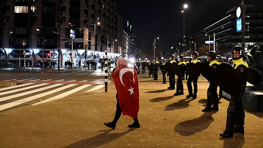 Manifestante con una bandera turca frente a los policías antidisturbios en Rotterdam