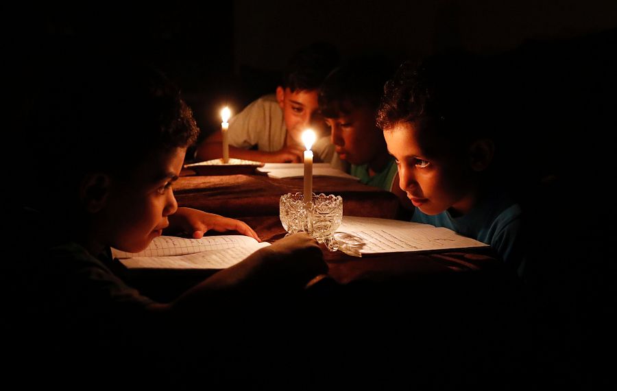 Niños palestinos leen a la luz de las velas debido a los cortes de electricidad en Gaza.