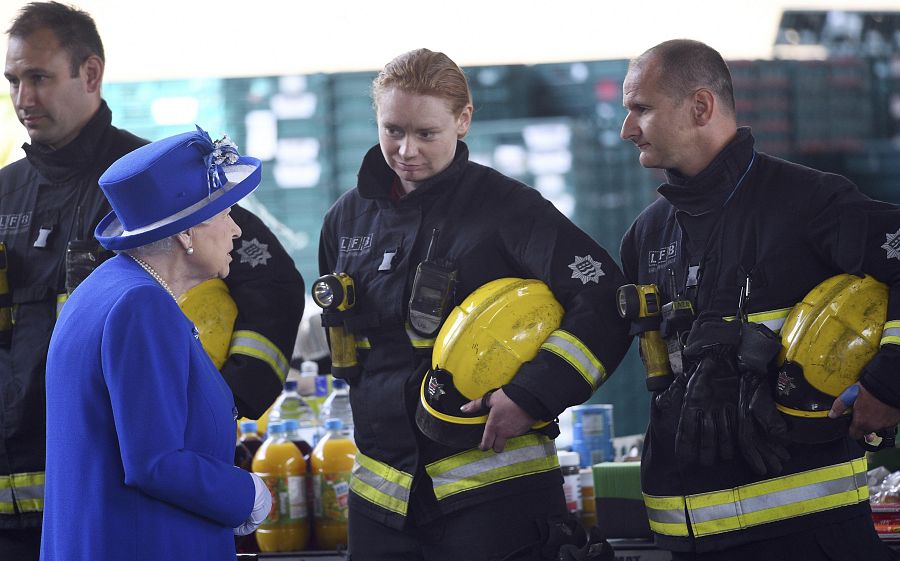 La reina Isabel II conversa con bomberos durante una reunión con residentes de la torre Grenfell en Londres.