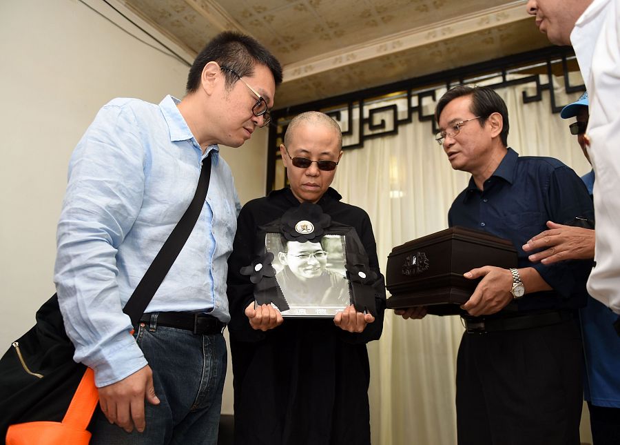 La viuda de Liu Xiaobo y su hermano, Liu Xiaoguang, sostienen un retrato del Nobel de la Paz durante su ceremonia de incineración en Shenyang.