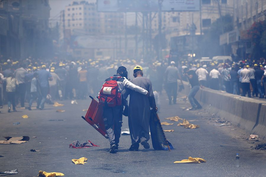 Un miembro de la Cruz Roja ayuda a uno de los manifestantes heridos en las protestas ante el puesto de control de Qalandiya, en Cisjordania