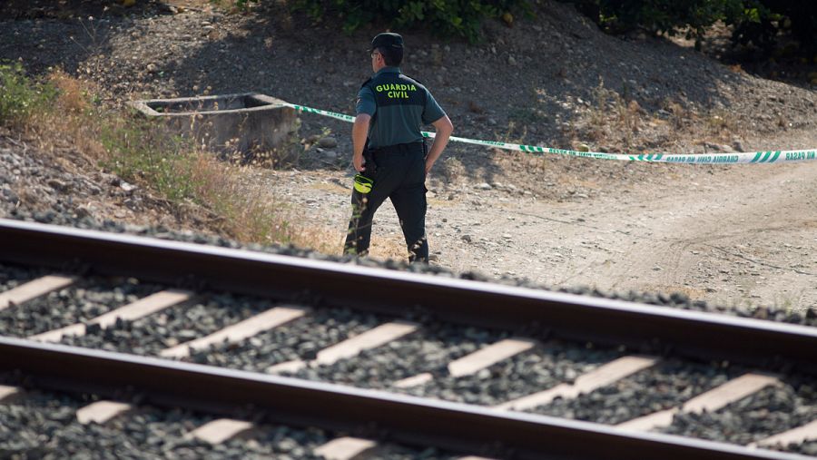 Un guardia civil inspecciona la zona acotada de la vía férrea donde se halló a la niña de tres años.