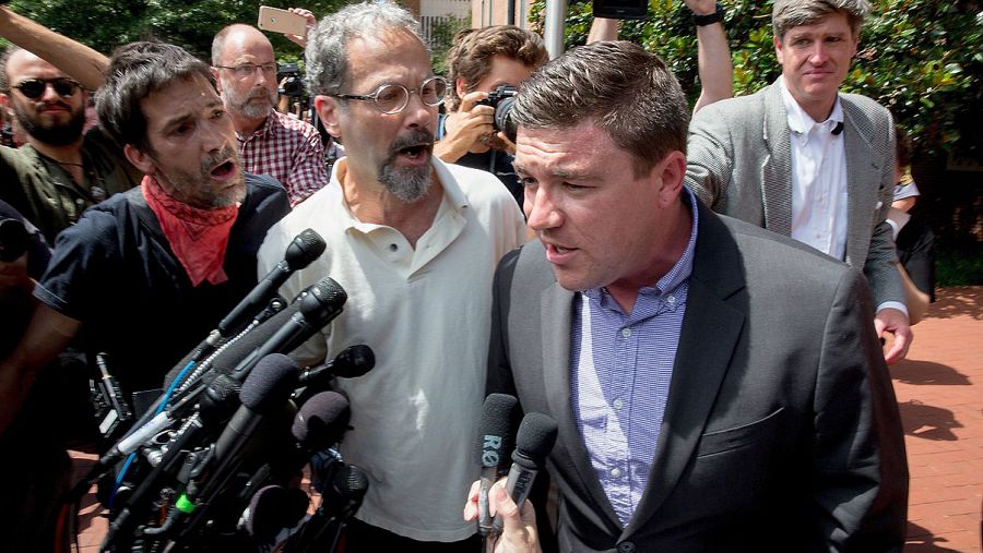 Jason Kessler (derecha, con chaqueta), convocante de la marcha racista de Charlottesville (Virginia, EE.UU.), habla acosado por varias personas durante una rueda de prensa tras el atentado del pasado sábado.