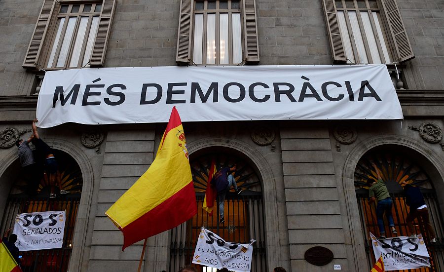 Manifestantes intentan descolgar una pancarta en la que pone 