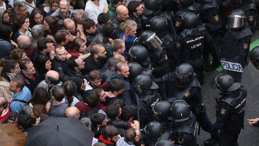 Los antidisturbios de la Policía Nacional bloquean la entrada de personas concentradas en el exterior de un colegio electoral en Barcelona