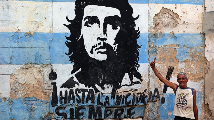 Un hombre posa junto a un grafiti del Che Guevara en La Habana