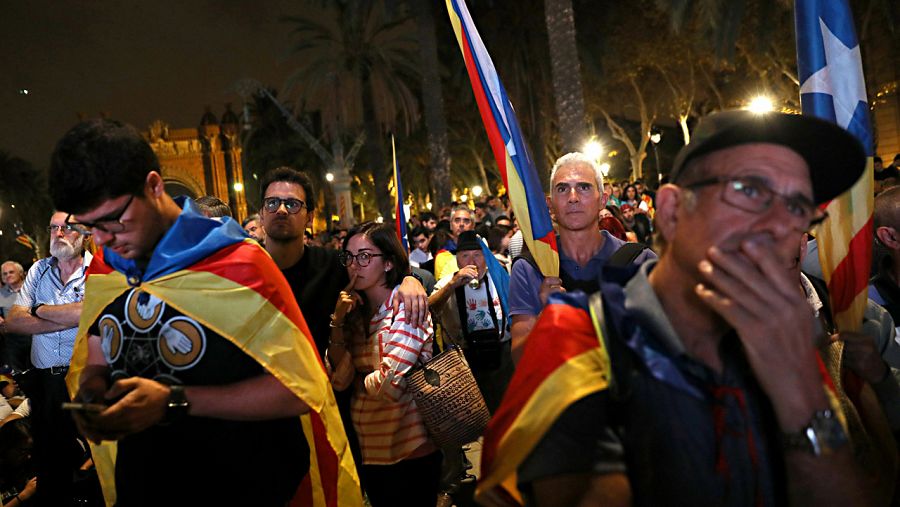 Varios de los independentistas congregados junto al Parlament siguen la declaración del Puigdemont