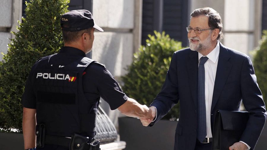 Rajoy saluda a un agente a su entrada al Congreso de los Diputados.