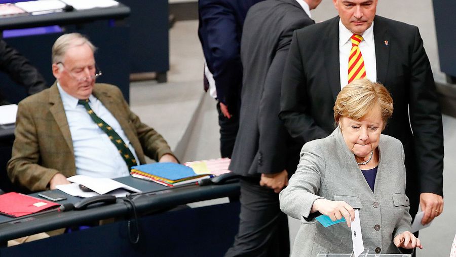 La canciller alemana Angela Merkel vota en el Parlamento. Detrás, el diputado de AfD Albrecht Glaser