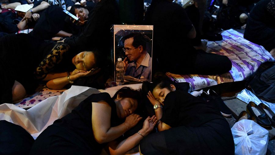 Unas mujeres duermen en la calle antes de la procesión por el funeral