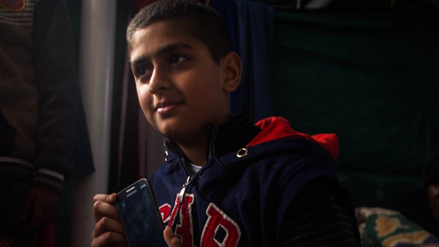 Uno de los niños muestra su móvil, que es lo más importante para él, aunque no funcione