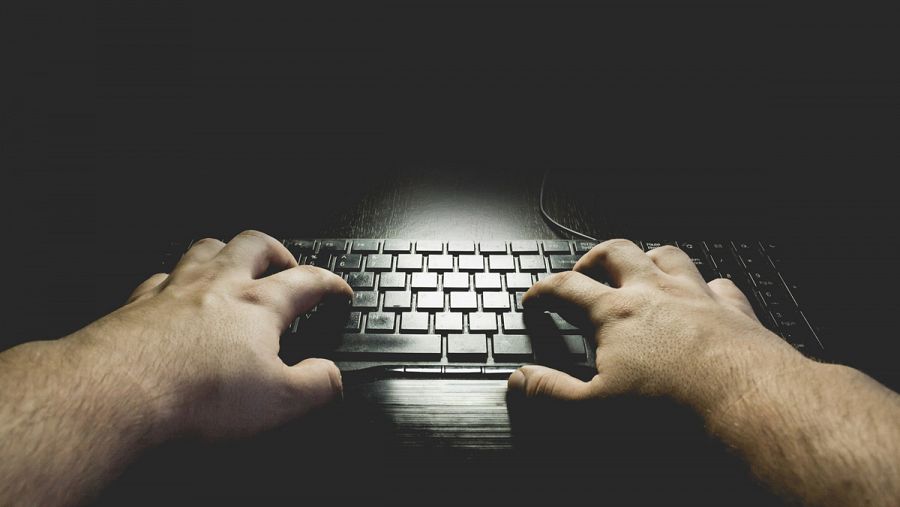 Un hombre escribe en el teclado de su ordenador