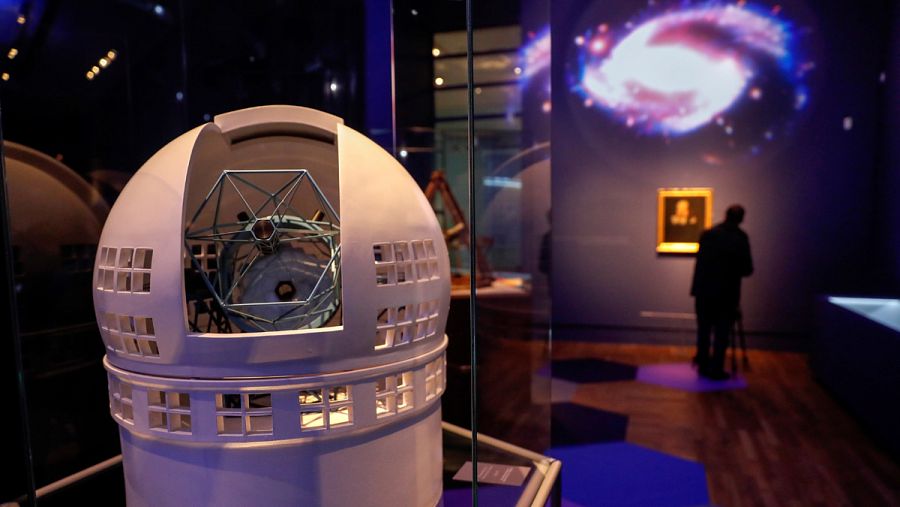 Reproducción en miniatura del Gran Telescopio Canarias, con un retrato de Galileo de fondo.
