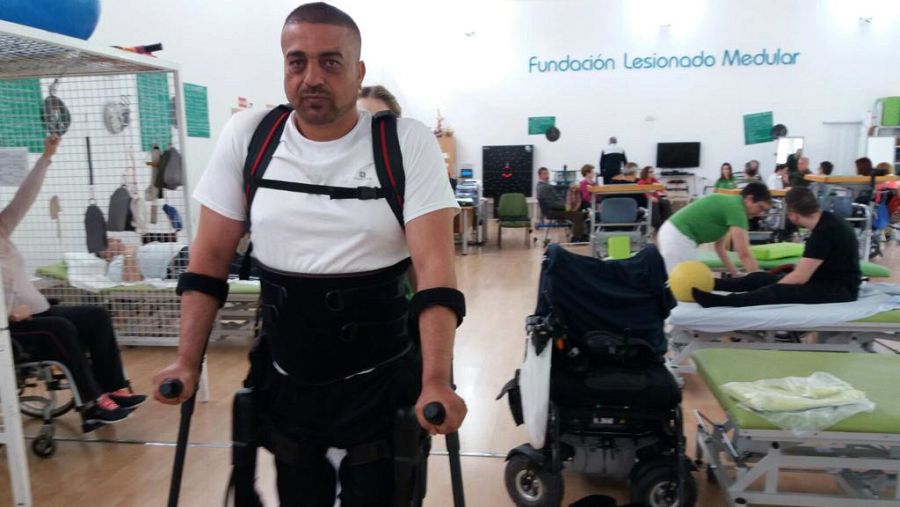 Genaro se ayuda de un exoesqueleto para caminar.
