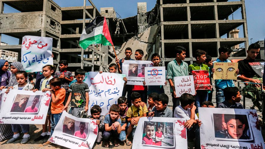 Jóvenes palestinos muestran fotografías de los dos adolescentes muertos junto al edificio atacado por Israel