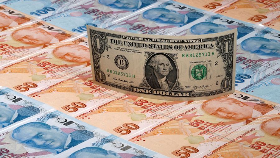 Un billete de un dólar sobre láminas de billetes de 50 y 100 liras turcas