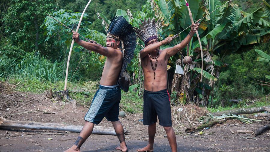 Dos jóvenes indígenas se disponen a disparar sus arcos.