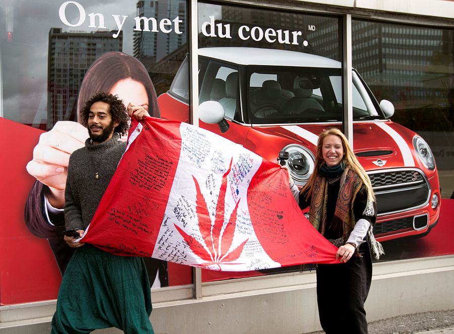 A couple holds a flag as they wait in line for the opening of Quebec Cannabis Society store on the day Canada legalizes recreational marijuana in Montreal