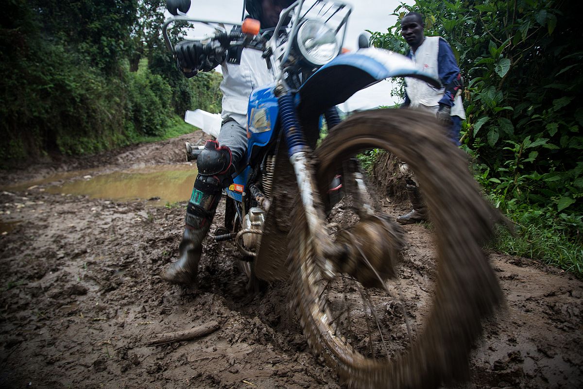 Primer plano de la rueda delantera de una moto que avanza hacia la cmara sobre el barro del camino.