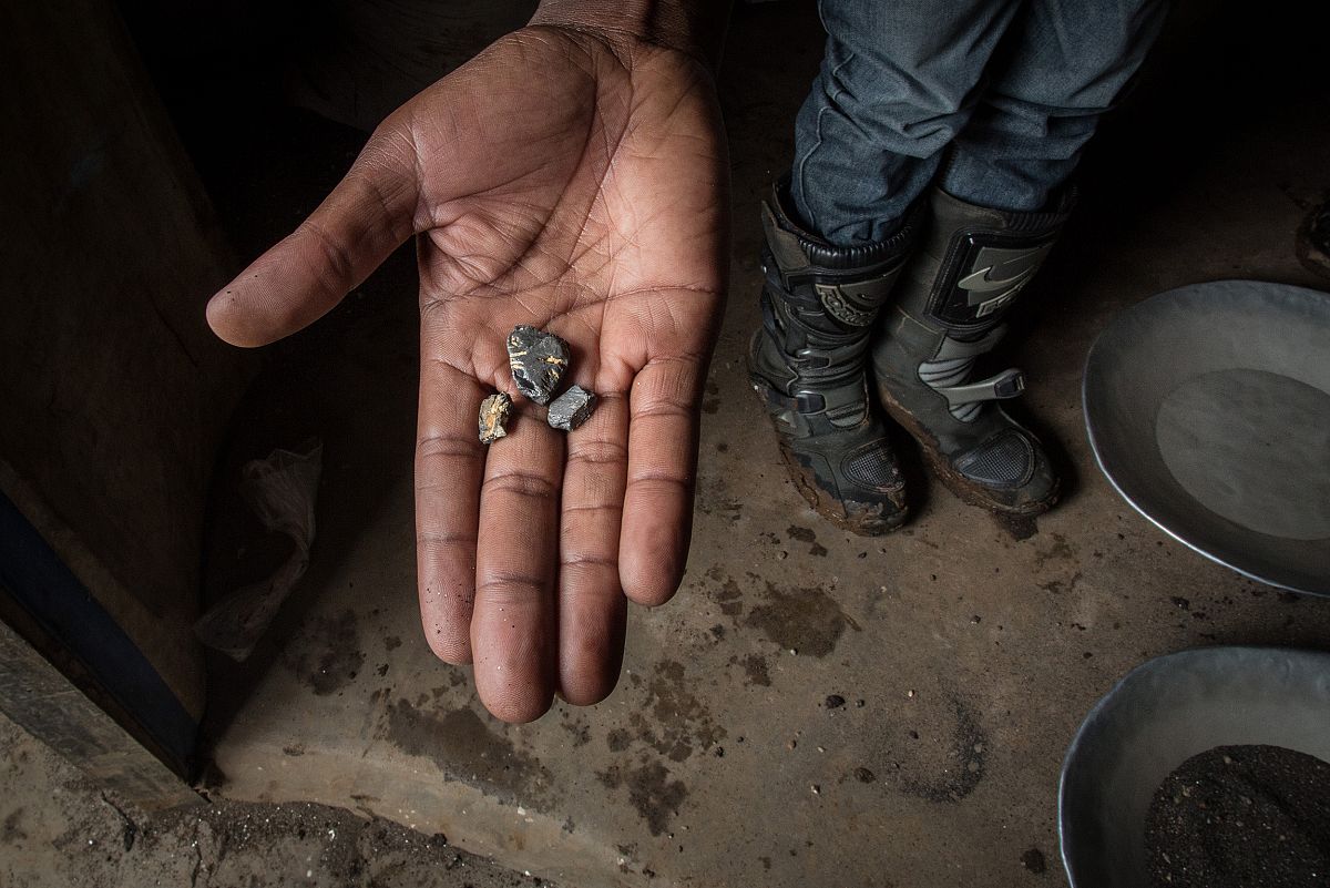 Primer plano de la mano de un minero mostrando piedras de coltn.