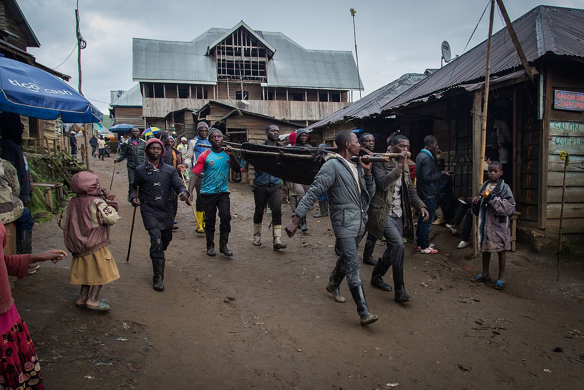 Unos lugareños llevan una camilla a hombros camino del hospital por las calles de Numbi.