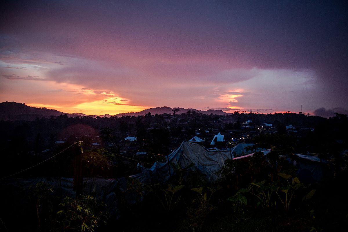 Atardecer sobre la poblacin de Lulingu. El sol se pone tras los montes cercanos mientras se encienden algunas farolas entre casas y tiendas de campaa.