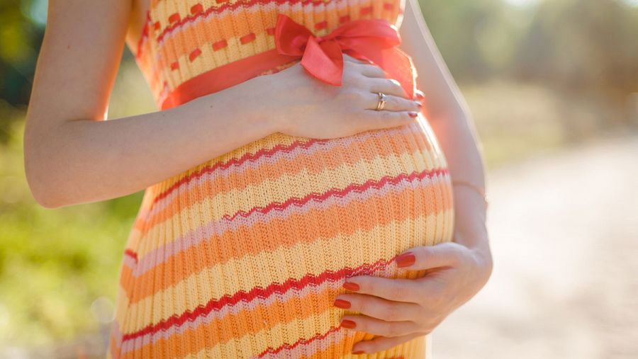 Mujer embarazada con la mano sobre la tripa