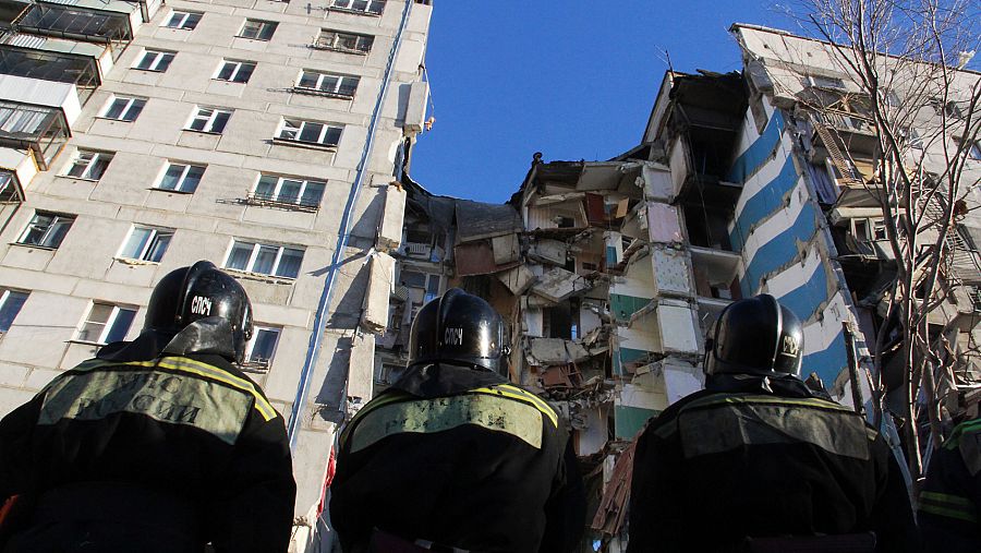 Tres bomberos contemplan el edificio derrumbado en Rusia