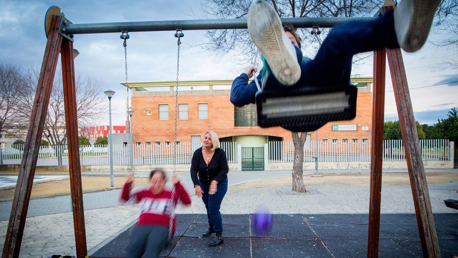 Una madre columpia a sus hijos.