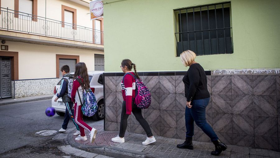 Una madre acompaña a sus tres hijos al colegio en Sevilla.