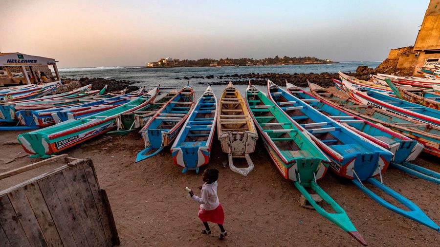 Una niña senegalesa pasa junto a piraguas de pesca en el pueblo de Ngor, de 400 años, en el extremo más occidental de África, Dakar, Senegal