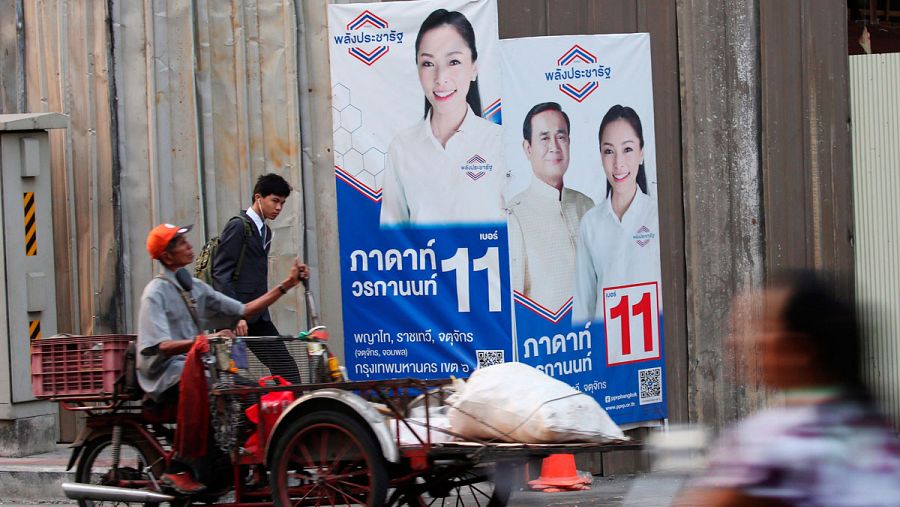 Un hombre monta un vehículo para recolectar basura reciclable frente a un cartel de la campaña electoral con un retrato del primer ministro tailandés y líder de la junta Prayut Chan-o-cha