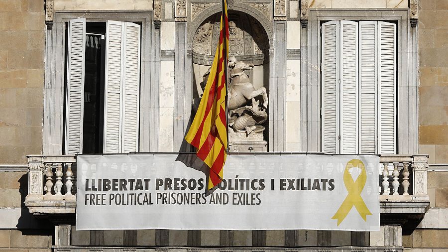 Vista del cartel reclamando la libertad de los líderes independentistas presos y un lazo amarillo en la fachada del Palau de la Generalitat