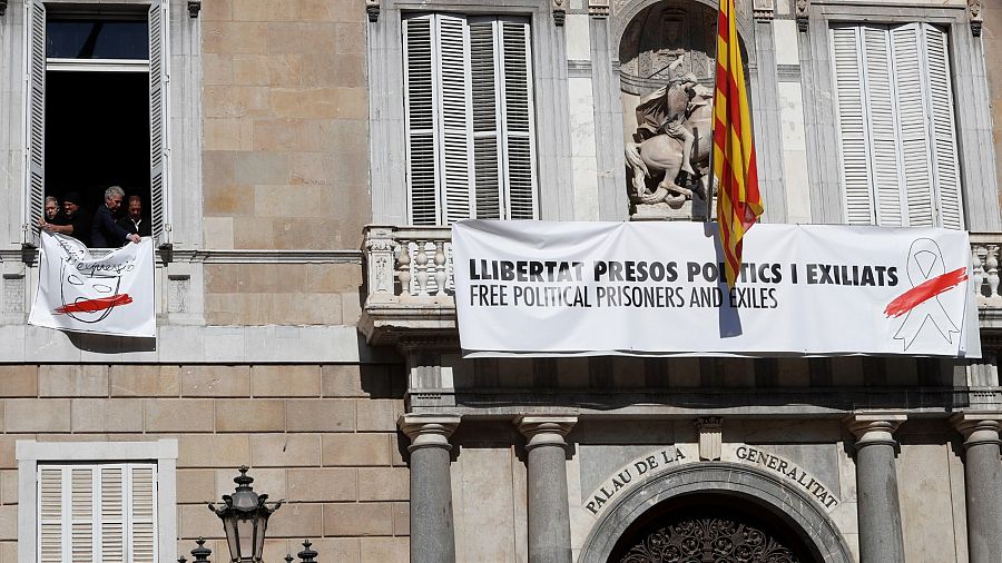 Pancarta con un lazo blanco sobre la anterior con un lazo amarillo en el Palau de la Generalitat